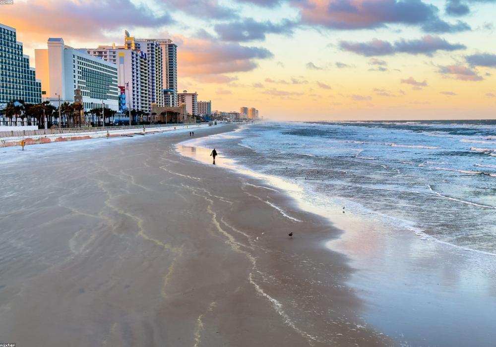 Playa al atardecer con paseo marítimo y hoteles frente al mar